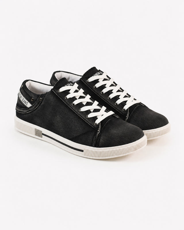 Black canvas sneakers with white laces and a textured finish, featuring a low-profile design and rubber sole.