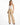 A model wears high-waisted, wide-leg beige pants paired with a delicate white camisole and stylish black heels.