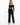 A model wearing tailored black pants paired with a cropped off-the-shoulder top and high-heeled sandals.