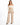 A model poses in wide-leg beige pants paired with a fitted off-the-shoulder top and stylish black heels.