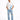 A man stands confidently wearing a white graphic t-shirt with blue designs and light blue distressed jeans.