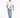 A man walks confidently in a white graphic t-shirt and distressed light blue jeans, paired with white sneakers.