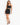 A model poses in a black crop top and matching fitted skirt, paired with strappy high-heeled sandals.