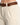 Light beige pants with side pockets, paired with a braided brown belt for a stylish look.