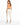 A woman stands with her back to the camera, wearing light-colored pants and a fitted orange top, paired with white sn...