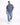 A man walks confidently in a loose-fitting blue shirt and distressed jeans, paired with white sneakers.