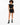 A model poses in a black cropped top and matching shorts with side cutouts, paired with black combat boots.