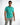 A man poses confidently in a turquoise polo shirt paired with light gray pants, showcasing a casual style.