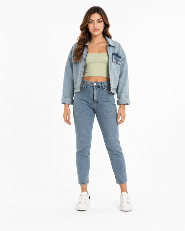 A woman stands confidently in light blue jeans paired with a cropped green top and a denim jacket.