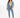 A model wearing light blue jeans with a cropped top and denim jacket, paired with white sneakers.