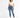 A woman stands confidently in a cropped white top and fitted blue jeans, paired with white sneakers.