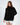 Model wearing a Celine black oversized knit turtleneck sweater with a unique distressed fringe hem against a white backdrop.