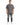 A man stands wearing a loose-fitting gray t-shirt with a small text design, paired with distressed black jeans and wh...