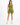 A model poses in a fitted olive green outfit featuring a one-shoulder top and matching shorts.