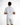 A person wearing a light gray shirt with embroidered text on the back, paired with white shorts featuring colorful pa...