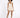 A model poses in a light beige romper with a fitted bodice and flared shorts, paired with black heels.