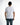 A man stands with his back to the camera, wearing a fitted white t-shirt and blue jeans.