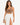 A woman poses in a fitted brown top and a flowing white skirt with high side slits, showcasing a stylish look.