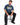 A man sits on a stool wearing a blue graphic t-shirt featuring colorful designs and a positive message.