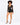 A model poses in a sheer long-sleeve top and high-waisted black shorts, paired with strappy heels.