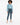 A model stands wearing a light blue long-sleeve top, high-waisted dark jeans, and white slide sandals.