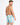 A man with short hair poses from the back, wearing colorful swim trunks featuring a palm tree pattern.