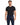 A man wearing a fitted black t-shirt paired with navy pants featuring a chain accessory.
