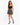 A woman poses in a fitted black top and a flared skirt with a playful print, paired with strappy black heels.