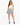 A woman stands confidently in a playful, patterned skirt paired with a fitted white tank top and stylish black heels.