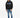 A man stands wearing a black hoodie with blue accents, paired with light blue jeans and stylish sneakers.