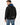 A man wearing a black sweatshirt with blue lettering on the hood and text on the back, paired with blue jeans.