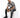 A man sits on a white cube, wearing a black and white patterned short-sleeve shirt with distressed jeans and black sn...