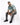 A man sits on a white cube, wearing a short-sleeve, tie-dye shirt with shades of teal and gray, paired with distresse...