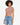 A model with curly hair wears a fitted, short-sleeve, cropped top paired with distressed denim shorts.