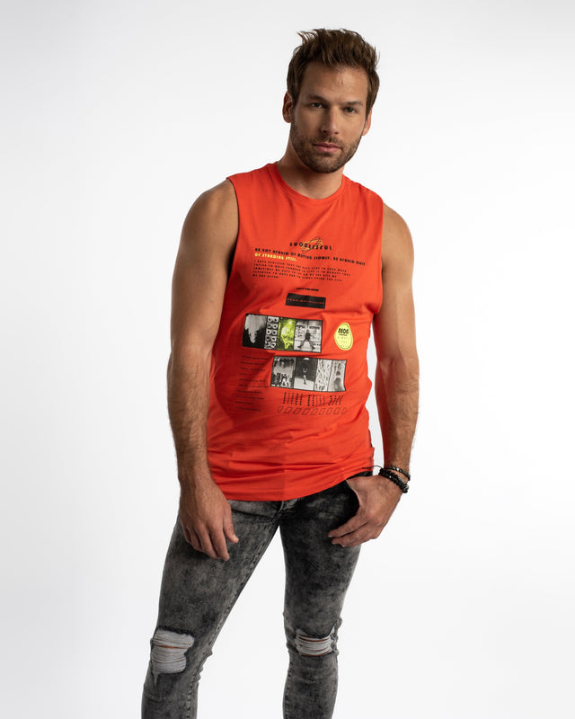 A man wearing a sleeveless orange top with graphic text and images, paired with distressed black jeans.