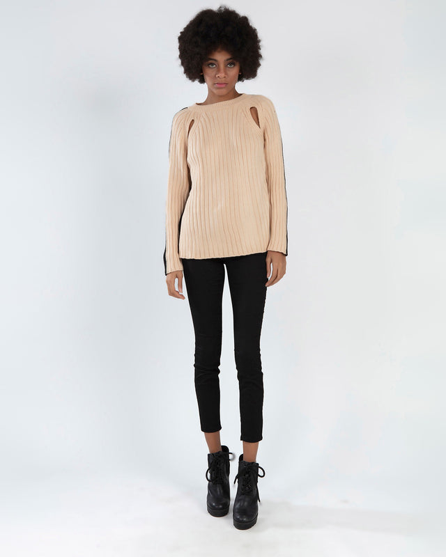 Lilith beige ribbed knit sweater with shoulder cut-outs and black side stripes, paired with black skinny jeans.