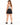 A woman with long hair wears a tie-dye tank top and black denim shorts, standing with her back to the camera.