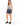 A woman stands confidently in denim shorts and a tie-dye tank top, paired with black sneakers.