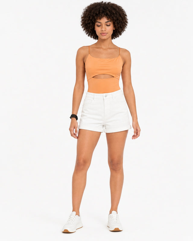Model wearing an orange bodysuit with a cutout detail, paired with white shorts and sneakers.