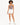 Model wearing a fitted bodysuit with a cutout detail, paired with white shorts and sneakers.