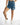 Model wearing Sunny Blue high-waisted distressed denim shorts with unique double waistband and frayed raw hem.
