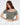 A model poses in a soft, cropped, off-the-shoulder top in a muted green shade, paired with a white skirt.