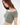 A model showcases a soft, off-the-shoulder, cropped top in a muted green hue with short sleeves.