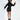 A model poses in a black hooded dress with a unique asymmetrical hem and stylish ankle boots.
