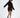 A model showcases a black oversized hoodie dress with a unique hemline and side slits, paired with stylish black ankl...