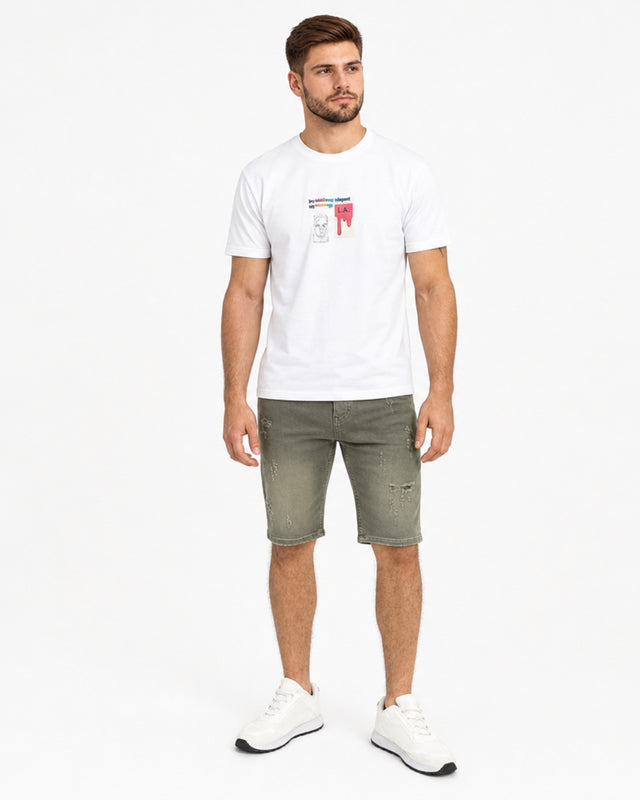 A man stands wearing a white graphic t-shirt and olive green distressed shorts, paired with white sneakers.