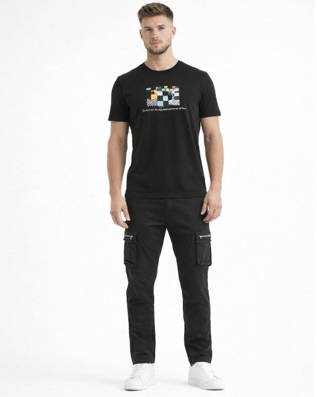 A man stands confidently in a black graphic t-shirt and cargo pants, paired with white sneakers.