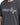 Gray t-shirt featuring bold white text and star graphics, worn by a person from the chest up.