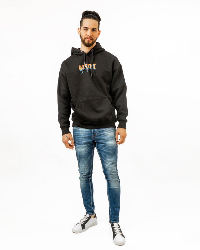Model wearing a Decent black oversized streetwear hoodie with orange drip graphic and blue skinny jeans.