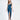 A model poses in a sleek, teal satin dress with a deep neckline and a thigh-high slit, paired with black heels.